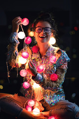 Happy woman wearing glowing jacket with sequins is holding light balls in her hands