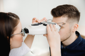 Man sits and smiles in an iron frame for selection of glasses lenses eyes reception ophthalmologist.