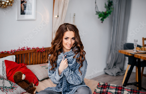 Beautiful Young Girl With Long Wavy Hair Sits On A Bed In A New