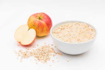 Oatmeal in white bowl and red apple on white background. Isolated on white. Healthy food