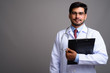 © Ranta Images - Young handsome bearded Persian man doctor against gray backgroun