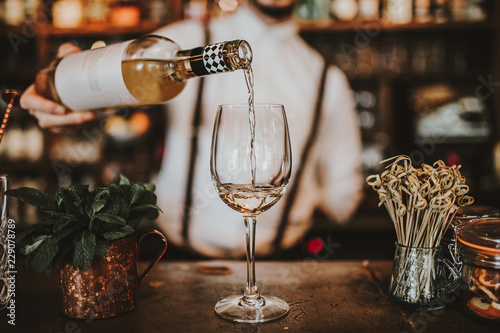 Cuadros en Lienzo Close up shot of a bartender pouring white wine into a glass