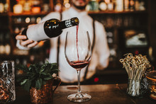 Close Up Shot Of A Bartender Pouring Red Wine Into A Glass. Hospitality, Beverage And Wine Concept.