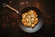 Traditional Orginal Fried Spicy Rice With Chicken Served In A Round Iron Wok. Placed On Rusty Dark Background. Top View With Copy Space.