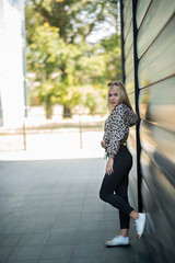 Photographing a girl during autumn near a high-tech glass building with a blurred background of the park