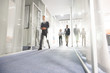 © Seventyfour - Blurred motion of modern business people crossing illuminated office corridor while hurrying to their workplaces, corporate company
