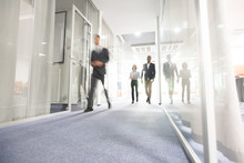 Blurred Motion Of Modern Business People Crossing Illuminated Office Corridor While Hurrying To Their Workplaces, Corporate Company