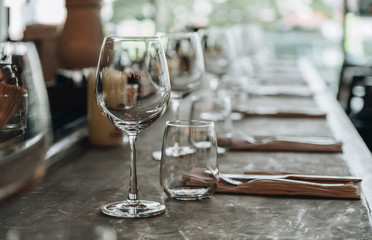 Empty glasses in the restaurant with knife and fork on wooden table, waiter prepare table to we;come customer