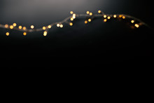 Abstract Christmas Lights On  Black  Background. Defocused  Glowing Light Bulb Garland, Copyspace