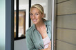 © goodluz - Blond woman welcoming people at entrance front door