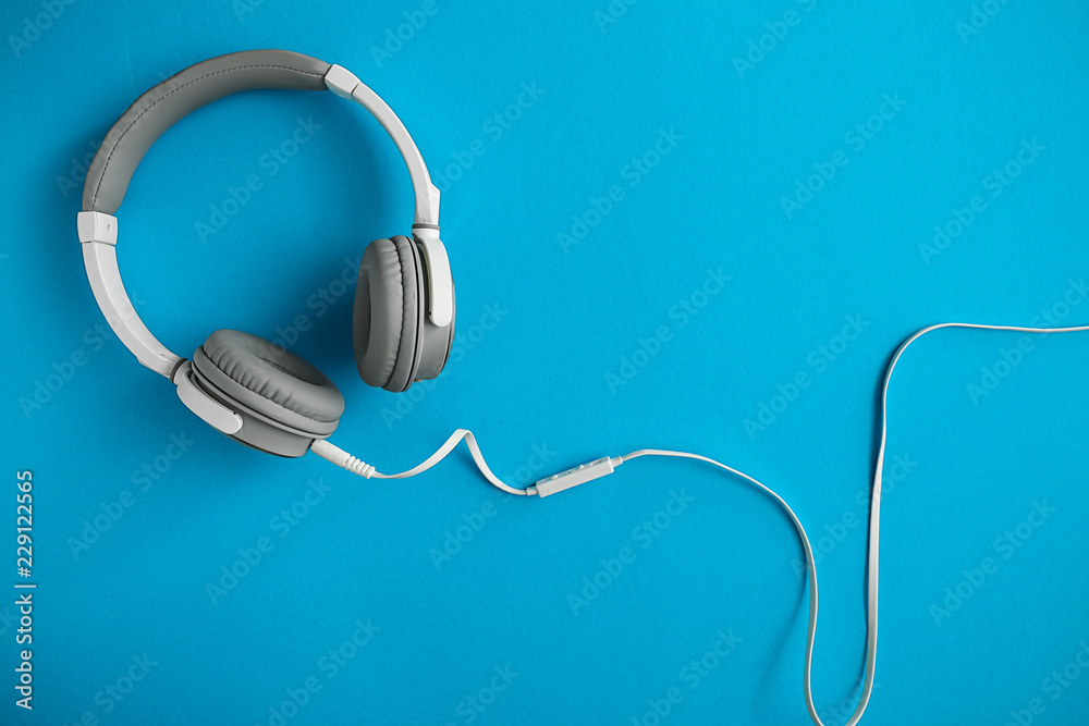 Modern headphones on color background