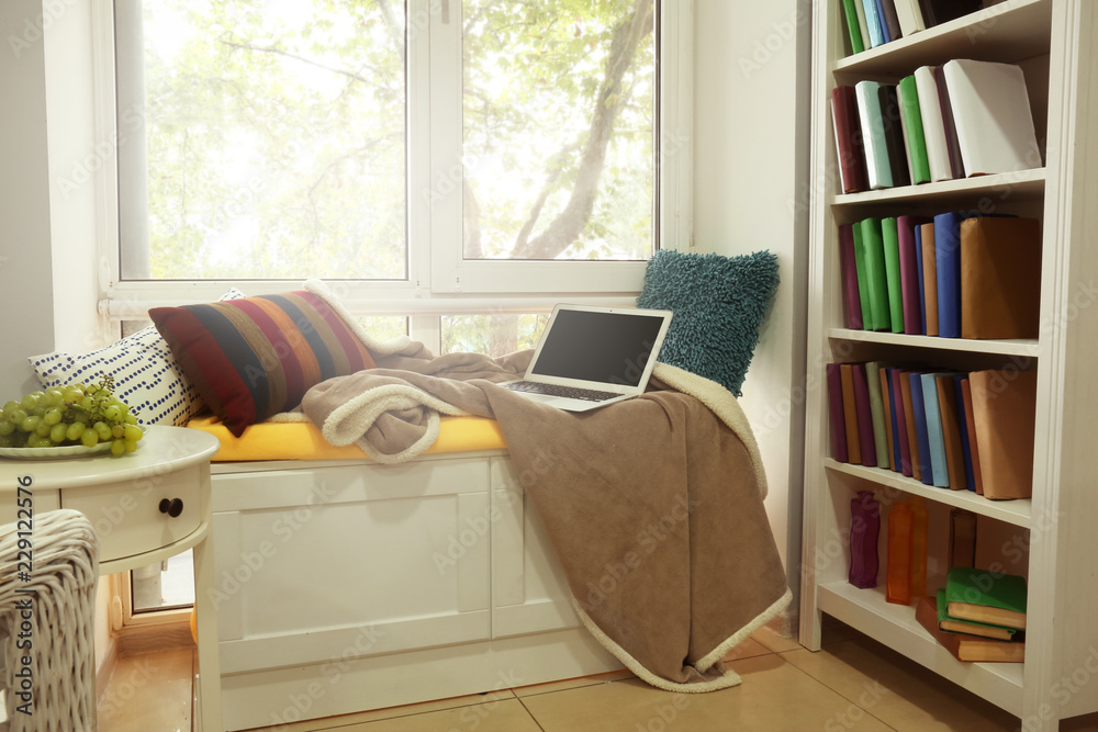 Cozy place for rest with soft pillows and laptop near window