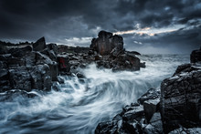 Moody Dramatic Skies And Large Waves Crash Onto Coastal Rocks