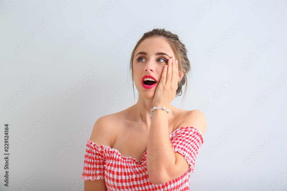 Surprised young woman on light background