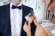 bride puts groom on boutonniere from roses on wedding day
