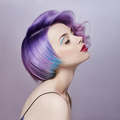 Portrait of a woman with bright colored flying hair, all shades of purple. Hair coloring, beautiful lips and makeup. Hair fluttering in the wind. Sexy girl with short  hair. Professional coloring