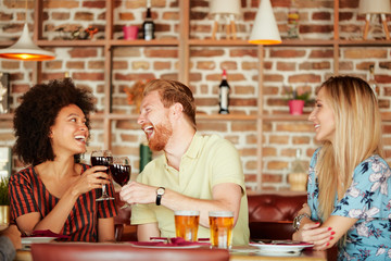 Wall Mural - Group of friends having dinner at restaurant. Friends cheering and drinking alcohol.