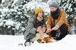 © pressmaster - Cheerful beautiful young couple in puffy jackets sitting by fire and getting hands warm while enjoying romantic date in winter forest