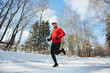 © pressmaster - Active retired man in sportswear running down winter road surrounded by trees