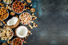 Various Types Of Nuts - Walnuts, Pecans, Peanuts, Hazelnuts, Coconut, Almonds, Cashews, In Bowls, On A Dark Blue Concrete Table Top View
