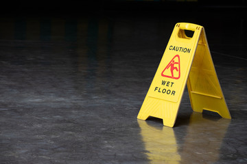 wet floor sign on cement ground. yellow plastic warning sign.
