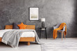 Grey and orange accents in simple and elegant bedroom with king size bed and painting on the empty concrete wall, real photo
