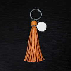 Orange Leather Tassel key ring on black wooden background. Fashion leather key chain for decoration.