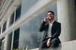 © Jacob Lund - Smiling business person taking on mobile phone sitting outdoors