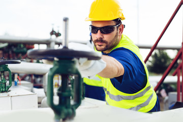 Poster - Oil worker closes the valve on the oil pipeline