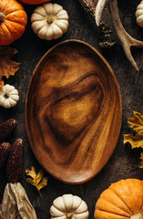 Wall Mural - empty wooden dish on a dark background with autumn decorations. top view. copy space.