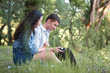 © soleg - young couple sitting on the grass in the forest and looking on sunset, listen to radio, summer nature, bright sunlight, shadows and green leaves, romantic feelings