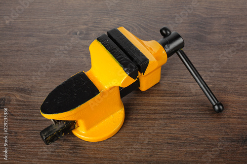 Fotografija  Metalwork tool - Yellow with black a vise wood background