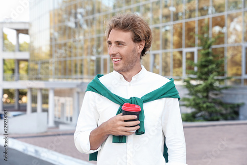Fotografía Portrait of handsome young man with cup of coffee on city street
