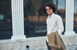 © iuricazac - Handsome young positive businessman with glasses posing outdoors. College male student on the street. Smart guy in casual wears white shirt and spectacles with curly hair walking on street
