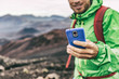 © Maridav - Hiker man taking photo with phone holding blue cover smartphone during outdoor activity in nature landscape. Hiking sport lifestyle young tourist on adventure.
