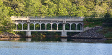 Distant View Of An Old Bridge With Cracked Concrete On A Tidal River On The Coast Of Maine.