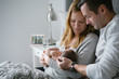 © Rob and Julia Campbell/Stocksy - Happy new family of three cuddling in the bed together at home