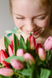 © Helen Rushbrook/Stocksy - Smiling preteen girl holding a large bouquet of spring tulips.