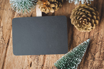 Poster - Top view of blank blackboard with xmas tree and gold pine cone on grunge wood table .winter holiday greeting card.space for display of design or content.