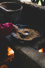 A Hand Stirring Coffee Beans Over A Fire In Indonesia