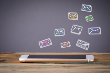 Wall Mural - e mail marketing concept. Media Technology concept. Mobile phone on a wooden table and a gray background