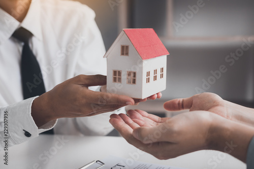 Fotografía Real estate agent congratulations to new buyer by giving house model to client in the agency office