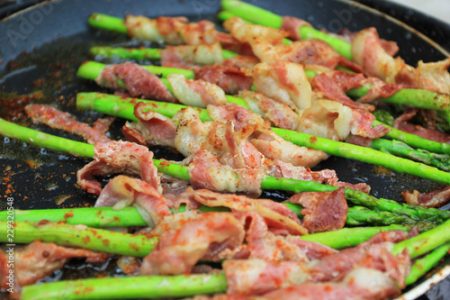 Fotografía Raw bacon wrapped green asparagus in frying pan on dark background