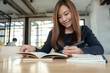 © Farknot Architect - Closeup image of a beautiful asian woman writing on blank notebook on table in cafe