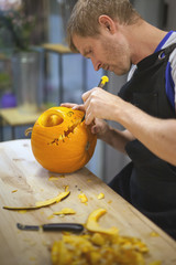 Wall Mural - Man carves a pumpkin to decorate the Halloween