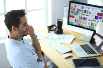 Fototapete - Portrait of young designer sitting at graphic studio in front of laptop and computer while working online.