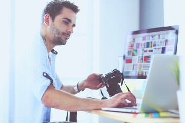 Fototapete - Portrait of young designer sitting at graphic studio in front of laptop and computer while working online.