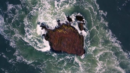 Canvas Print - Drone video of waves hitting a rock in the ocean 