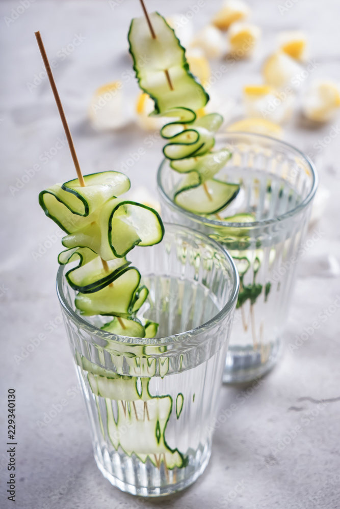 Glasses of fresh cucumber water on grey table