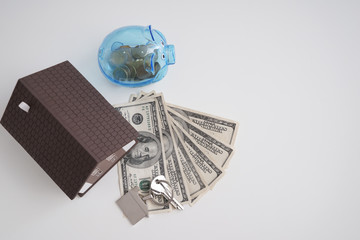 Poster - Piggy bank with money, house model and keys on white background. Concept of saving money for buying new house